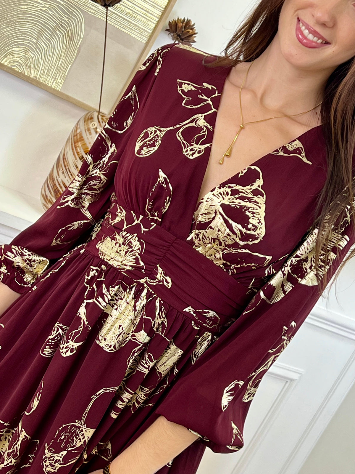 Robe longue bordeaux élégante aux détails dorés, idéale pour les occasions spéciales. Son col V et ses manches longues apportent une touche raffinée, tandis que l’élastique au dos assure un confort parfait. Entièrement doublée jusqu’à mi-longueur, elle allie style et aisance dans des nuances subtiles de bordeaux et doré.