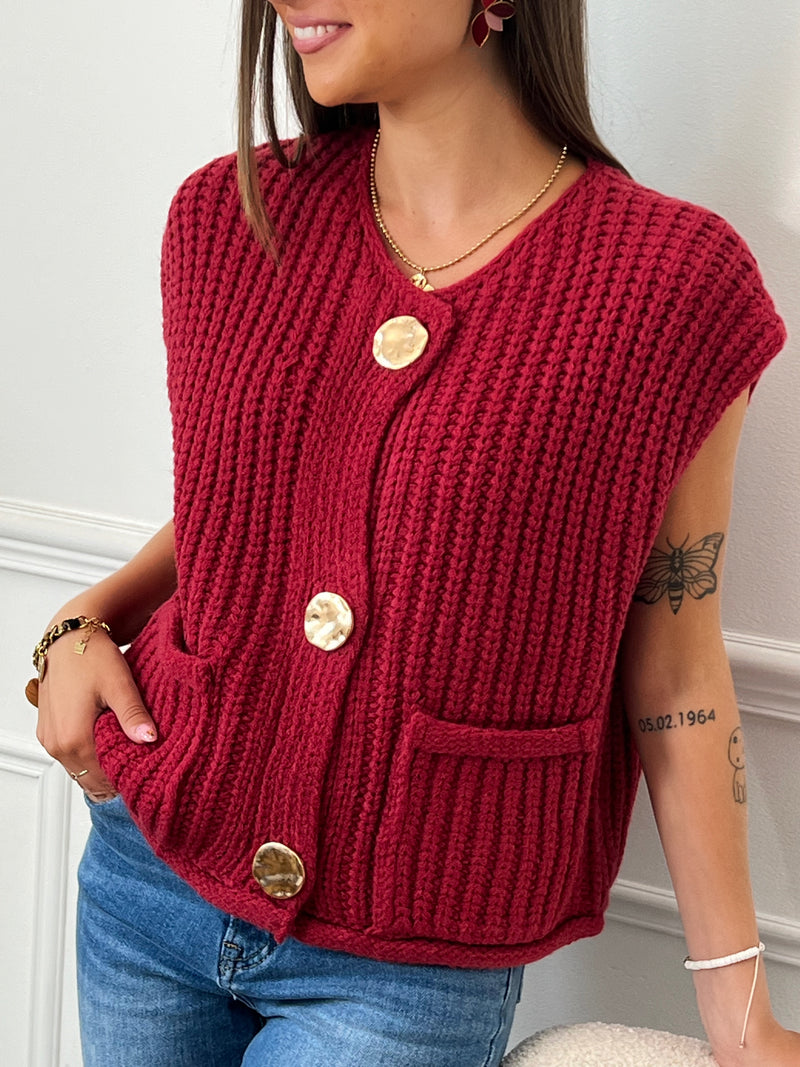 Voici le gilet bordeaux Caliope! Avec son col rond, ses 3 gros boutons dorés et ses 2 poches sur le devant, il est parfait pour toutes occasions. Sans manches et épais, il vous gardera au chaud tout en ajoutant une touche élégante à votre tenue. Un must-have pour votre garde-robe!