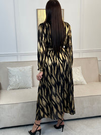 Robe festive Laina, l'allure sophistiquée pour vos soirées. Cette création élégante allie le noir profond et les touches dorées pour une présence rayonnante. Le col cache-cœur flatteuse épouse votre silhouette tandis que la taille élastique offre un confort optimal.