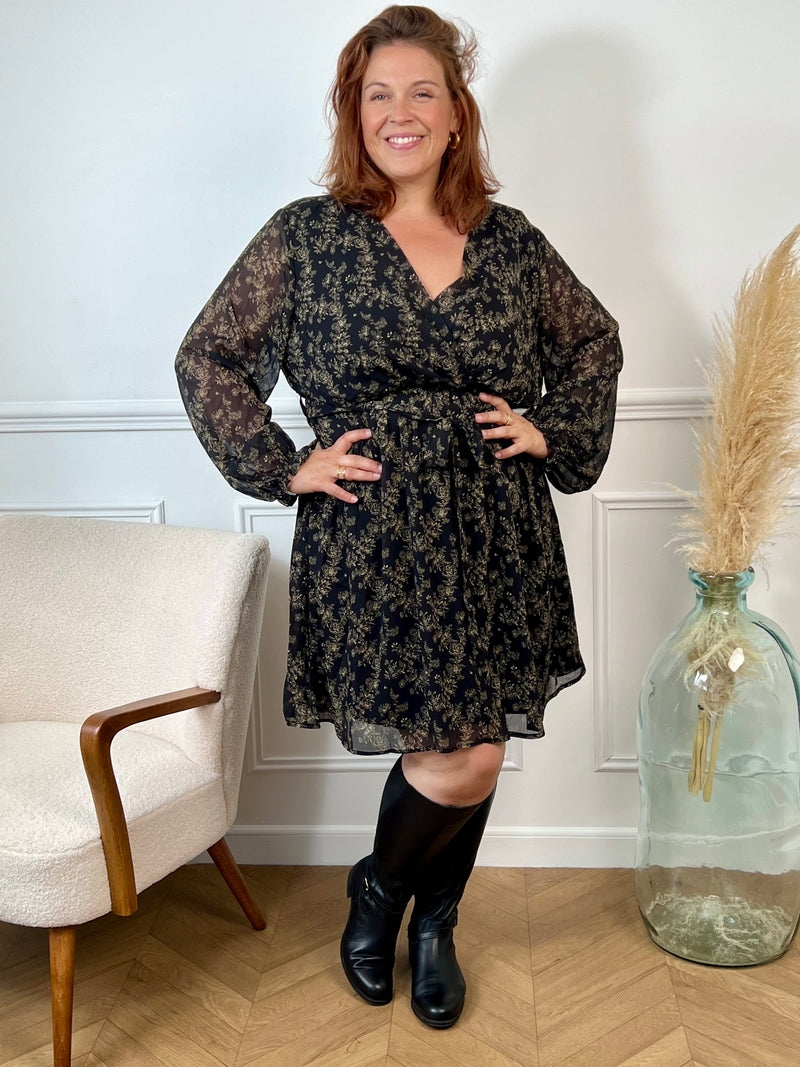 La robe courte Timy offre confort et élégance avec ses manches longues, son col cache-cœur et sa ceinture amovible. Ses motifs floraux en noir et beige donnent une touche élégante et féminine à cette pièce facile à porter au quotidien ou pour des occasions spéciales.