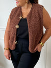 La veste moumoute sans manches Eda allie douceur et style. Conçue pour offrir un confort optimal, elle présente un col en V élégant et des broches dorées délicates sur le devant, qui ajoutent une touche sophistiquée.