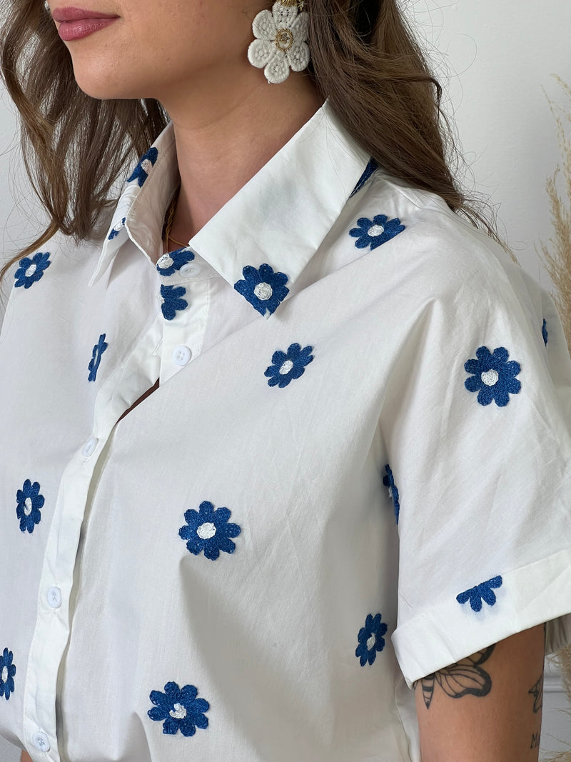 Découvrez notre chemise blanche et bleue : Jihane ! Avec ses manches courtes et sa broderie de fleurs bleues et blanches, cette chemise est à la fois élégante et décontractée. Ajoutez une touche de couleur à votre tenue tout en restant chic.