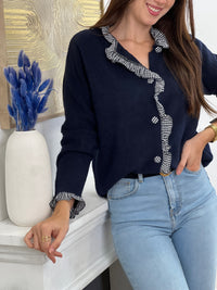 Élégance et originalité se rencontrent avec ce gilet bleu marine. Ses finitions à volants à carreaux au col, aux poignets, le long des boutons et sur toute la ligne apportent une touche raffinée et pleine de charme. Un essentiel revisité pour sublimer tes looks du quotidien.