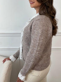 Élégant et raffiné, ce gilet taupe se distingue par ses délicats détails écru qui apportent douceur et contraste. Fermé par de charmants boutons en forme d’étoiles sertis de strass, il allie subtilement confort et éclat, parfait pour sublimer vos tenues avec une touche de chic discret.