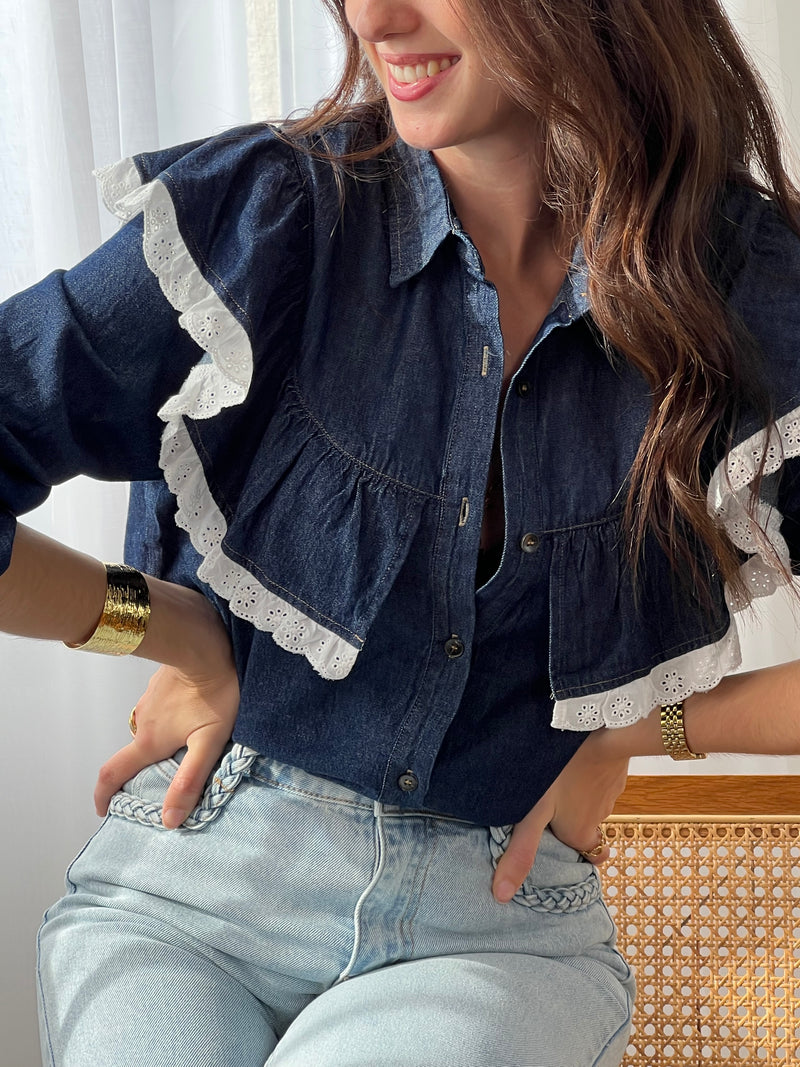 Cette chemise bleue Elyna allie élégance et confort avec son col classique et ses manches élastiques qui facilitent le mouvement. Les boutons sur toute la longueur permettent un enfilage pratique, tandis que le volant orné d'une broderie écrue apporte une touche délicate et raffinée.