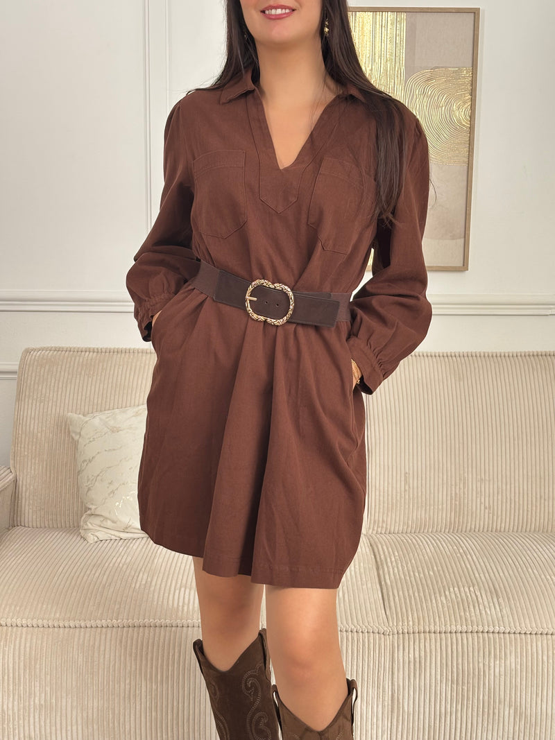 Cette robe courte en marron séduit par sa coupe ample et son col V à revers. Dotée de manches longues, de poches pratiques et de détails dorés aux poignets, elle allie confort et style au quotidien.