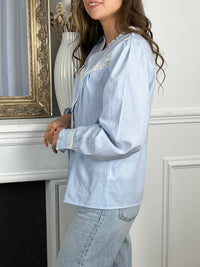 Cette chemise à rayures bleues et blanches est sublimée par des broderies raffinées, ajoutant une touche d'originalité. Parfaite pour une élégance décontractée, elle allie avec brio le charme traditionnel au chic contemporain, faisant d'elle un incontournable de toute garde-robe moderne