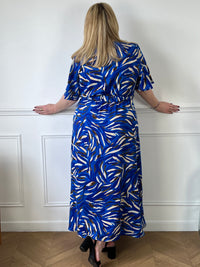Cette robe s'étend jusqu'aux pieds et est ornée de motifs bleus, ce qui lui confère un style distinctif. La ceinture peut être utilisée pour marquer la taille et ajouter une touche de structure à la silhouette. Cette tenue est parfaite pour des occasions spéciales ou pour un look décontracté mais chic.