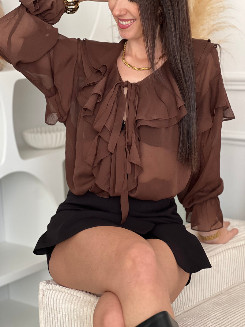 Découvrez la blouse Clelie, une pièce incontournable alliant élégance et confort. Confectionnée en marron riche, elle séduira par ses détails raffinés : col V flatteur, volants délicats aux épaules, manches et col pour une touche romantique.