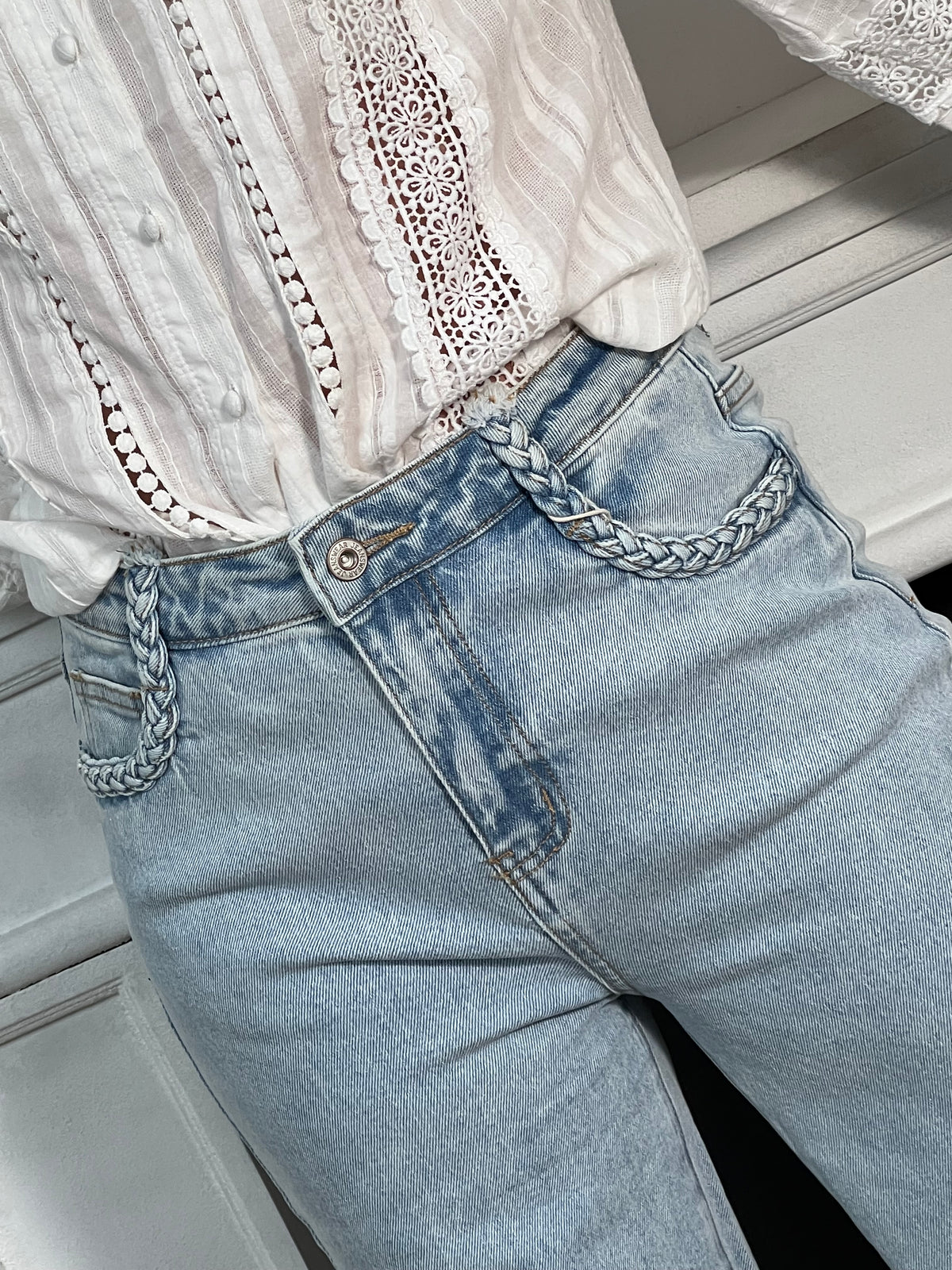 Jean bleu clair pour femme au style moderne et confortable, idéal pour un look tendance au quotidien. Ce modèle est doté de deux poches à l’avant et à l’arrière, de passants pour ceinture, ainsi que d’une fermeture éclair et d’un bouton pratique. Les détails tressés sur le devant apportent une touche originale et élégante à ce jean bleu incontournable.