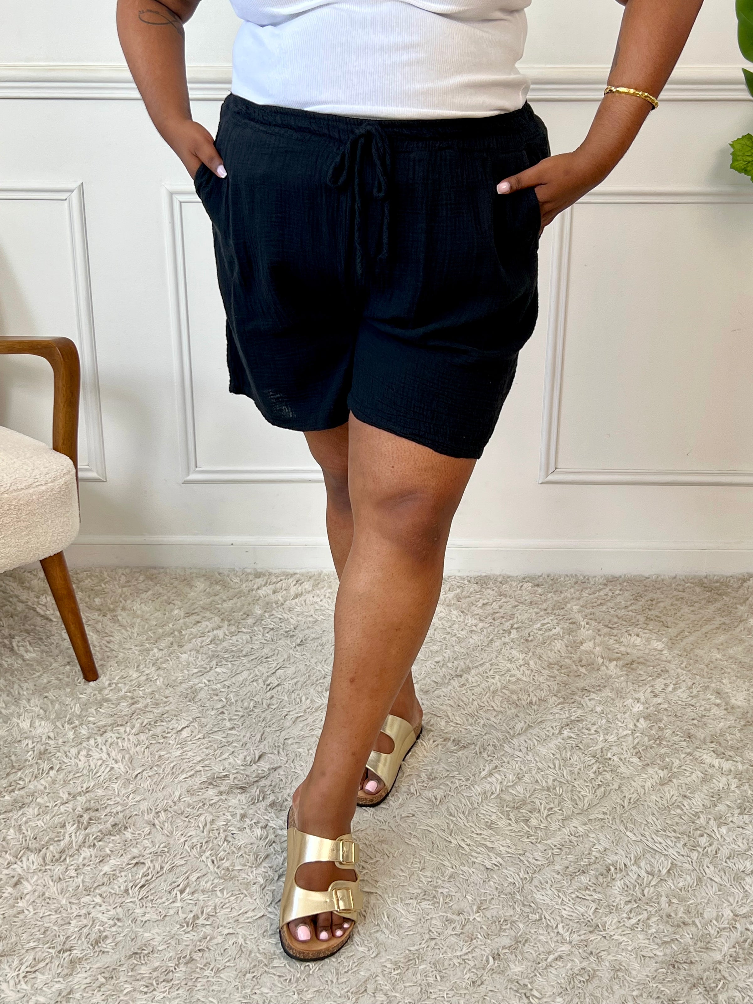 Ce short noir en gaze de coton allie confort et praticité grâce à sa taille élastique ajustable par un lien de serrage. Ses deux poches latérales offrent un espace pratique pour vos essentiels, tandis que sa matière légère assure une agréable sensation de douceur sur la peau.