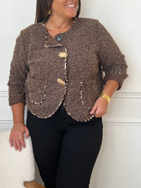 Chic et audacieuse, cette veste marron se démarque par son pourtour souligné d’une fine bande léopard, subtile touche de caractère. Pratique et élégante, elle est dotée de deux poches à l’avant et s’agrémente d’épingles amovibles dorées, offrant la possibilité de personnaliser votre look au gré de vos envies.