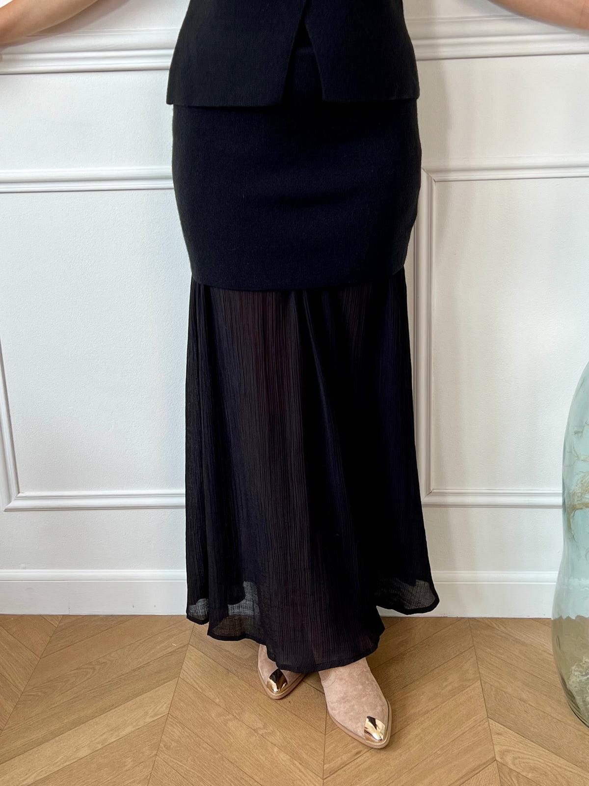 Jupe noire bi matière au style unique : une coupe courte effet pull qui épouse la taille, prolongée par une partie fluide et plissée pour un jeu de textures raffiné. Une pièce audacieuse et féminine, entre confort et élégance.