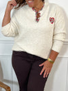 Ce pull beige grande taille allie douceur et élégance avec ses manches longues et son col en V orné de délicats motifs floraux. Un coeur brodé vient sublimer le devant, apportant une touche unique et féminine
