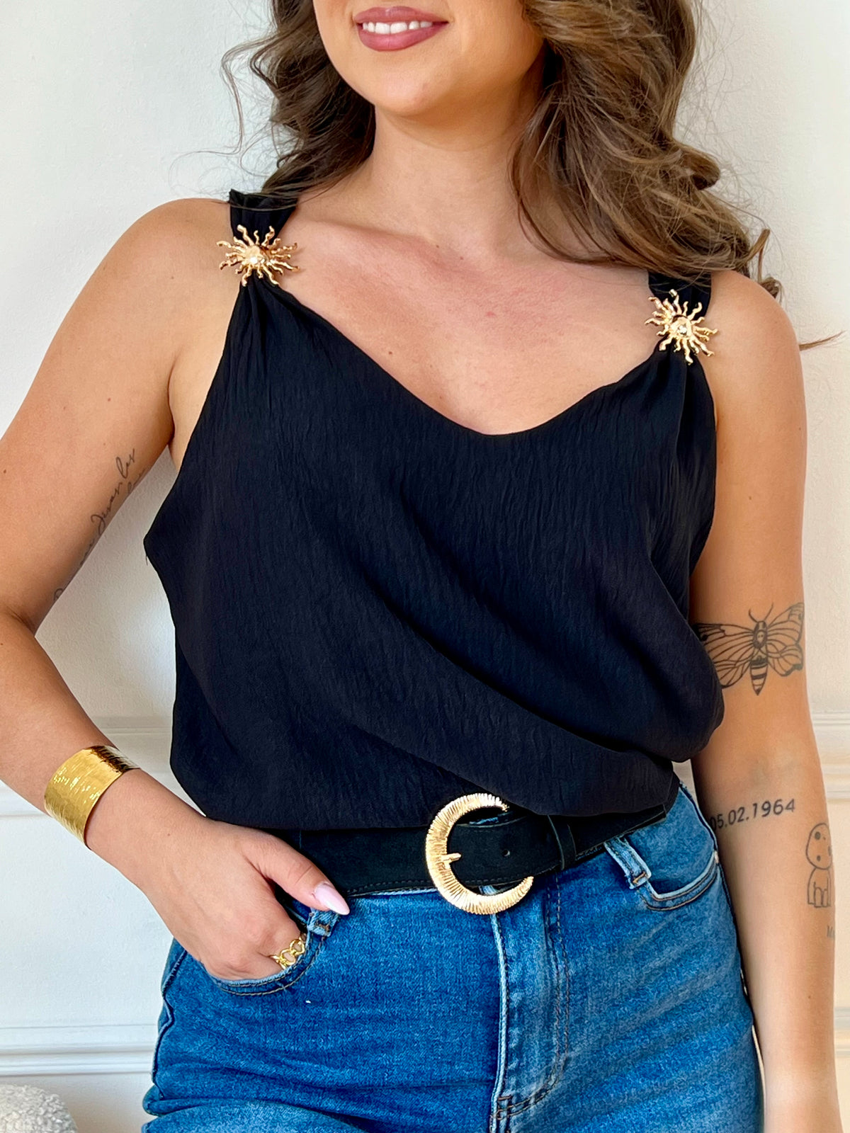 Ce top noir au design épuré séduit par ses bretelles ornées de délicats détails dorés. À la fois sobre et raffiné, il apporte une touche d’élégance à vos looks, de jour comme de nuit.