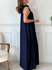 Sa coupe ample assure un confort optimal tout au long de la journée. Sans manches, elle présente des liens à nouer aux épaules pour une touche élégante et ajustable. Son col rond, à l’avant comme à l’arrière, est agrémenté d’un élastique qui garantit un maintien parfait sans contrainte.