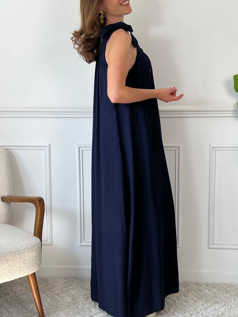 Sa coupe ample assure un confort optimal tout au long de la journée. Sans manches, elle présente des liens à nouer aux épaules pour une touche élégante et ajustable. Son col rond, à l’avant comme à l’arrière, est agrémenté d’un élastique qui garantit un maintien parfait sans contrainte.