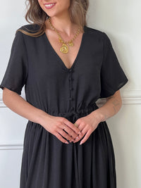 Cette robe longue noire est dotée d'un col en V flatteur, de boutons élégants à l'avant et d'une fente subtile qui ajoute une touche de sensualité. Parfaite pour un look sophistiqué et féminin, elle convient aussi bien pour toutes occasions.