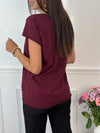 Ce tee-shirt bordeaux "Aliyah" allie confort et élégance avec ses manches courtes et son col rond classique. Sa touche distinctive, une inscription dorée sur le devant, apporte une subtile note de sophistication. Idéal pour un style décontracté mais soigné au quotidien.