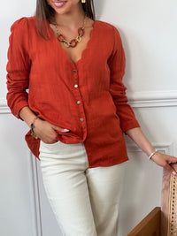 Une chemise à manches longues en gaze de coton terracotta, parfaite pour allier confort et style. Son col V festonné ajoute une touche délicate et féminine, tandis que la texture légère et douce du tissu assure une sensation agréable sur la peau. Idéale pour créer une tenue élégante tout en restant décontractée, cette chemise se distingue par son charme naturel et son allure intemporelle.