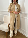 Trench beige femme avec ceinture, manches longues et col volanté pour une touche féminine. Boutons tout le long, doublure intérieure en carreaux vichy marron et écru, offrant élégance et confort. Coupe ample et deux poches latérales pratiques.