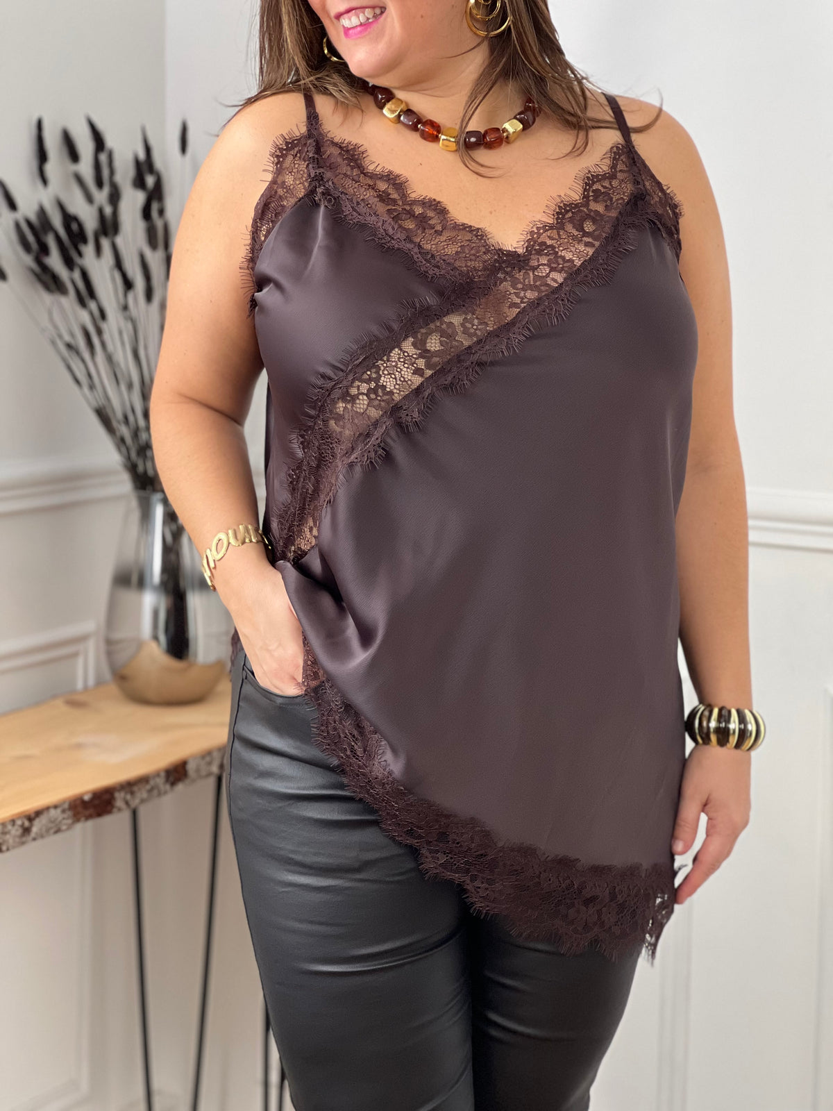 Découvrez le Top Léna, un incontournable de votre garde-robe. Confectionné en marron élégant, ce top séduisant arbore des détails en dentelle délicate au col et à l'ourlet pour une touche de féminité.