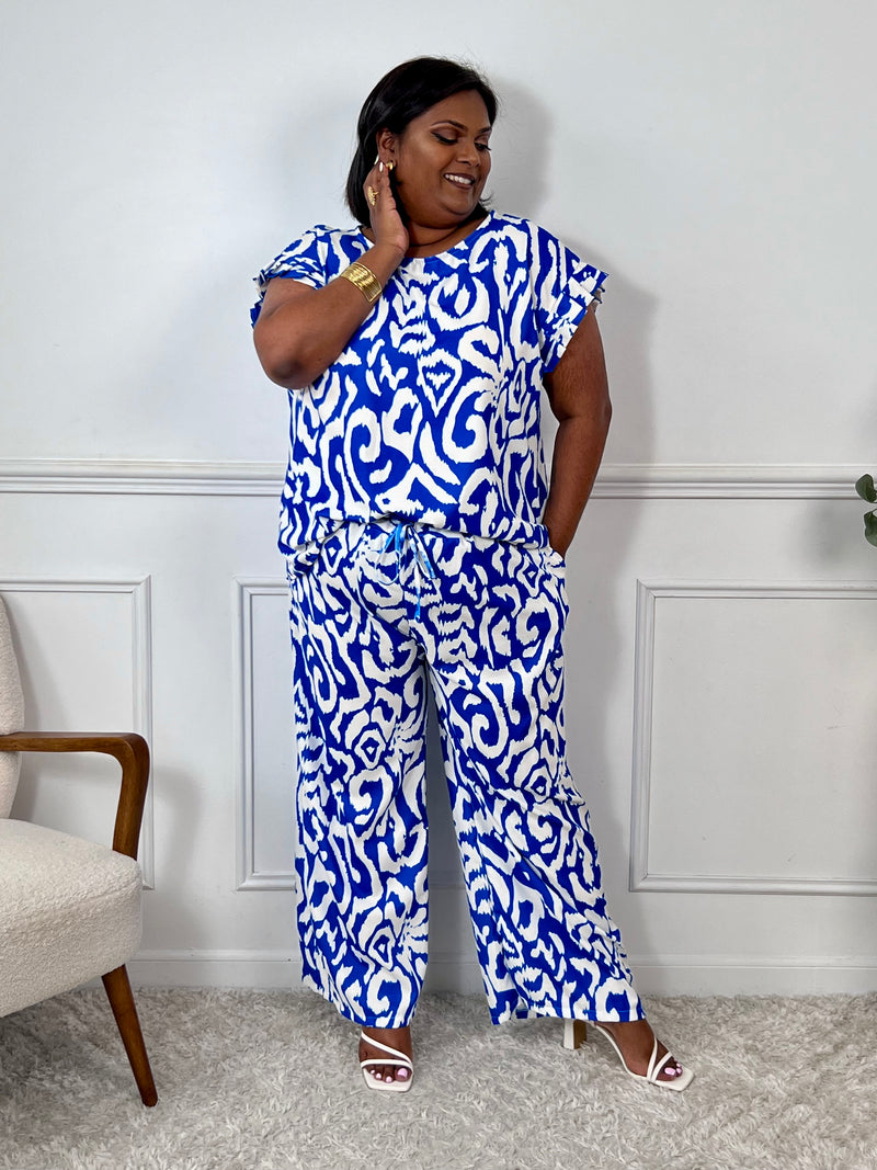 Sublimez votre silhouette avec le pantalon Linzy, une pièce audacieuse en bleu ornée de motifs élégants. Sa coupe ample célèbre vos courbes tout en garantissant un confort optimal pour toutes les occasions.