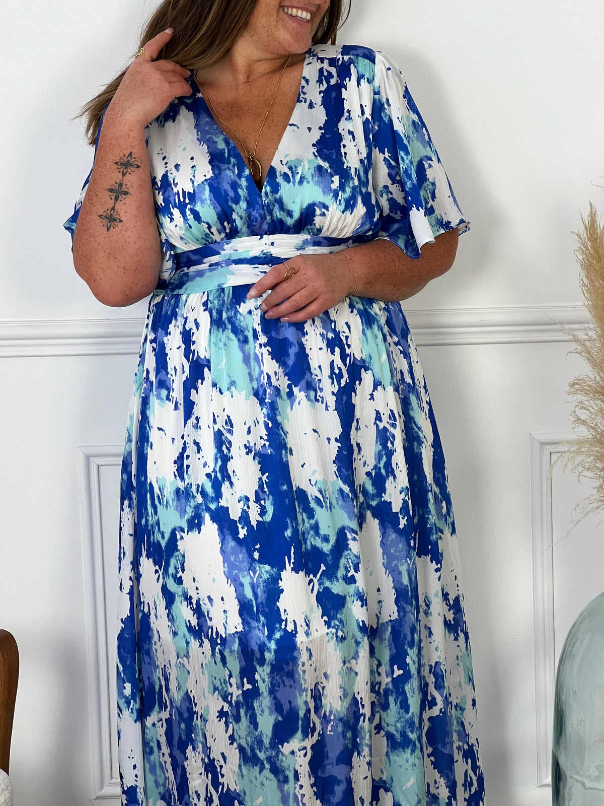 Cette robe longue arbore des motifs bleus et écrus, créant une harmonie visuelle délicate. Dotée d'un col en V élégant, elle allie sophistication et confort, parfaite pour les occasions estivales ou les sorties chics.