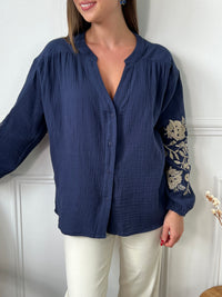 Cette chemise bleue pour femme allie élégance et raffinement grâce à ses détails dorés uniques. Conçue avec des manches longues et un col en V flatteur, elle se distingue par de sublimes broderies florales dorées sur les manches, ajoutant une touche de sophistication et de charme. Boutonnée sur toute la longueur, cette chemise est facile à porter pour un look chic et stylé en toutes occasions.