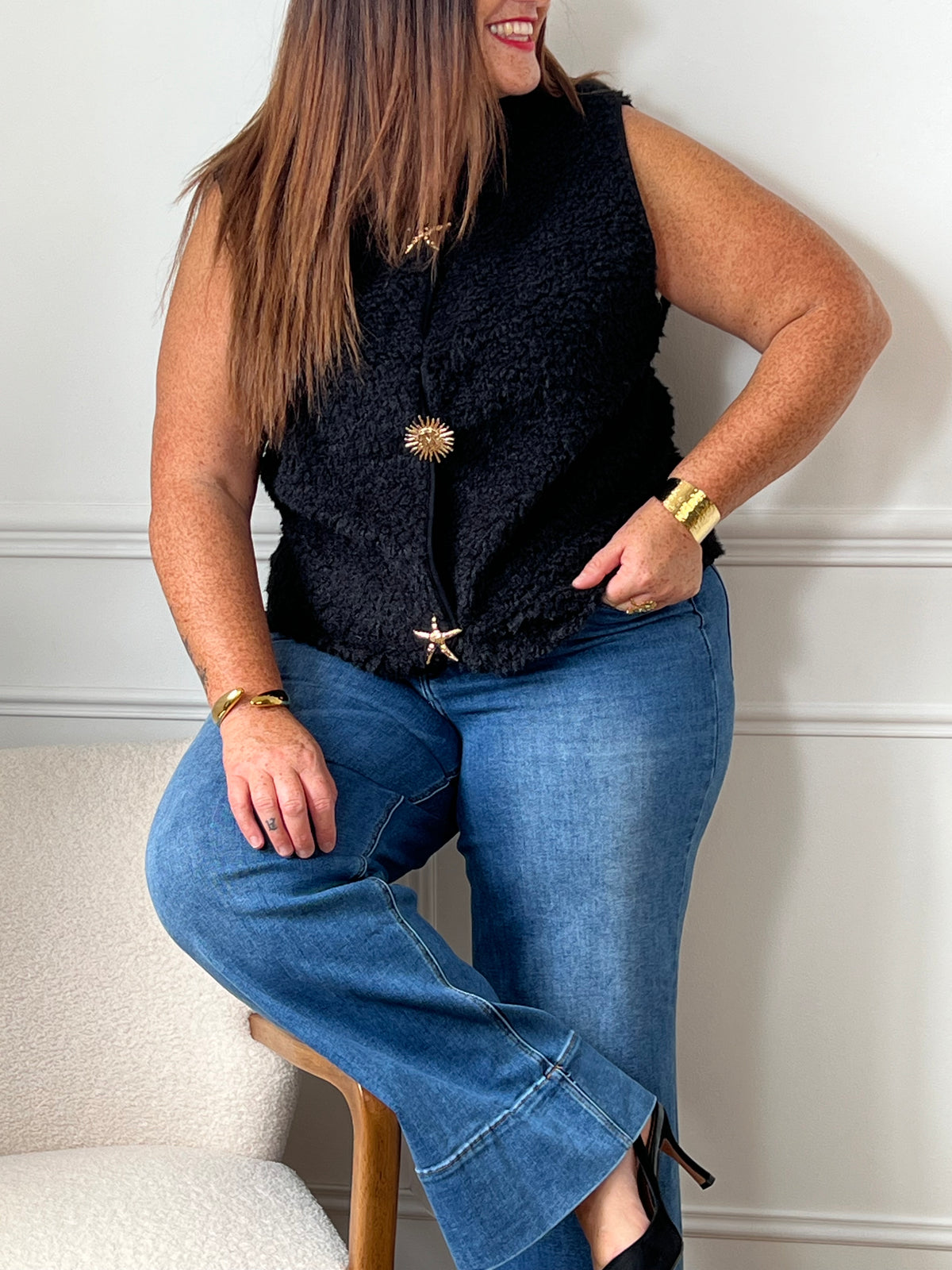 La veste moumoute sans manches Eda allie douceur et style. Conçue pour offrir un confort optimal, elle présente un col en V élégant et des broches dorées délicates sur le devant, qui ajoutent une touche sophistiquée.