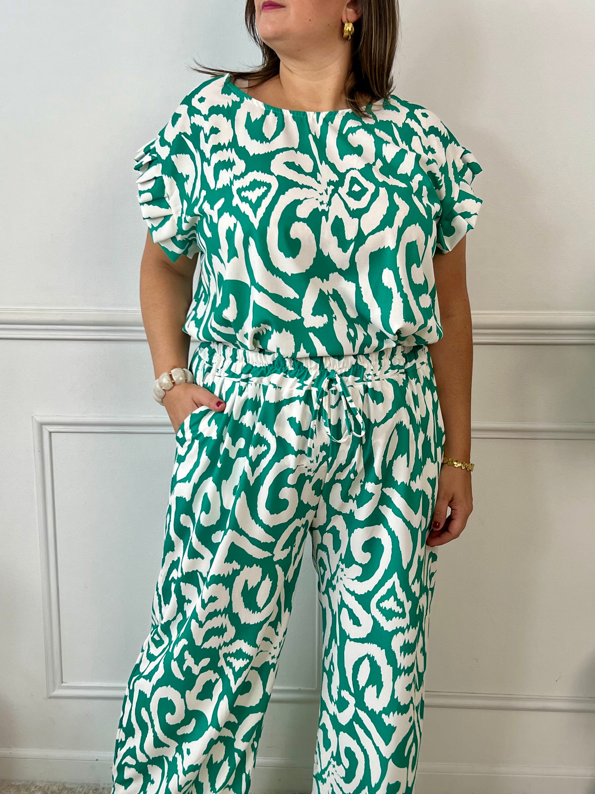 Léger et éclatant, ce top fluide vert et écru sans manches séduit par ses jolis volants aux épaules. Une pièce pleine de fraîcheur et de féminité, parfaite pour égayer vos looks avec une touche raffinée.
