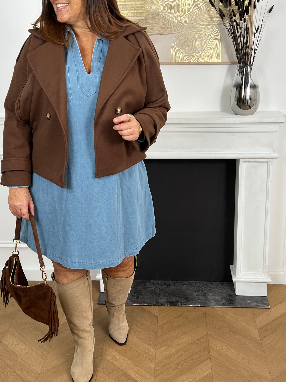 Cette robe courte en jean bleu clair séduit par sa coupe ample et son col V à revers. Dotée de manches longues, de poches pratiques et de détails dorés aux poignets, elle allie confort et style au quotidien.