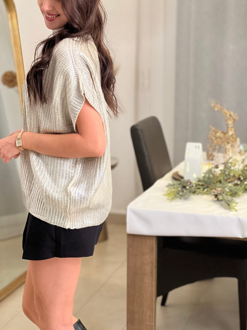 Élégant et moderne, ce pull sans manches beige s’illumine de détails argentés brillants sur l’ensemble du tissu. Une pièce chic et tendance, parfaite pour apporter une touche d’éclat à ton look.