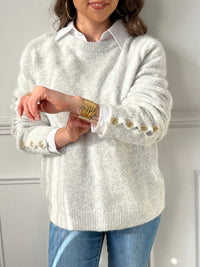 Ce pull gris apportera une touche de chaleur et d’élégance à votre tenue. Ses boutons dorés aux poignets ajoutent une note raffinée et sophistiquée. Confortable et tendance, il s’adapte à toutes les occasions.