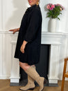 Cette robe courte noire grande taille, modèle Cora, allie élégance et confort. Ses manches longues et son col chemise apportent une touche sophistiquée, tandis que les boutons au col et aux manches accentuent son style raffiné.