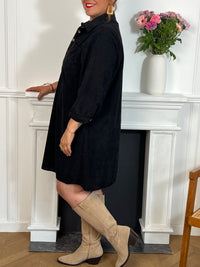 Cette robe courte noire grande taille, modèle Cora, allie élégance et confort. Ses manches longues et son col chemise apportent une touche sophistiquée, tandis que les boutons au col et aux manches accentuent son style raffiné.