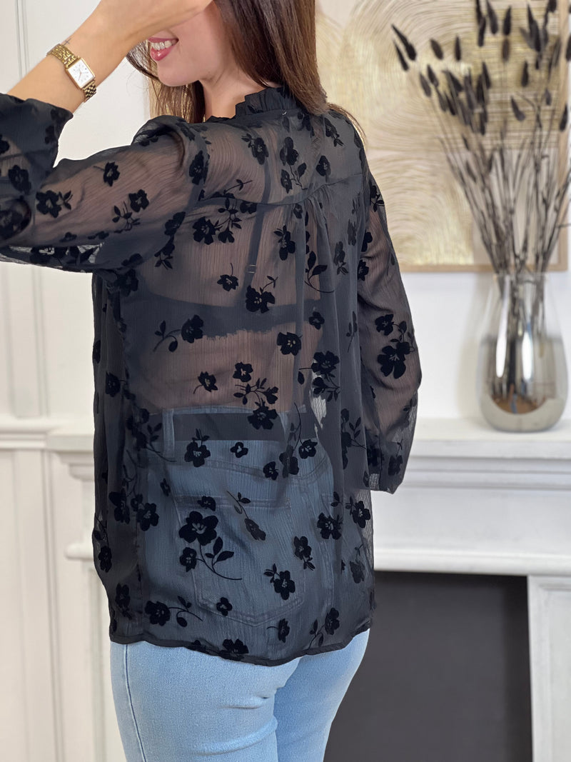 Cette chemise noire à motifs floraux Elenora allie élégance et délicatesse. Ses manches longues et son col rond apportent un charme classique, rehaussé par des volants subtils au col et aux manches.