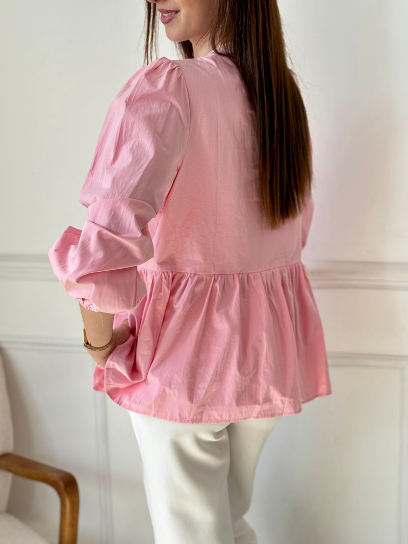 Cette blouse rose Adalia allie élégance et confort avec ses manches longues bouffantes, son col rond et ses poignets élastiques. Les liens à nouer sur le devant et les volants délicats sur le bas apportent une touche féminine et raffinée, idéale pour sublimer votre style au quotidien.