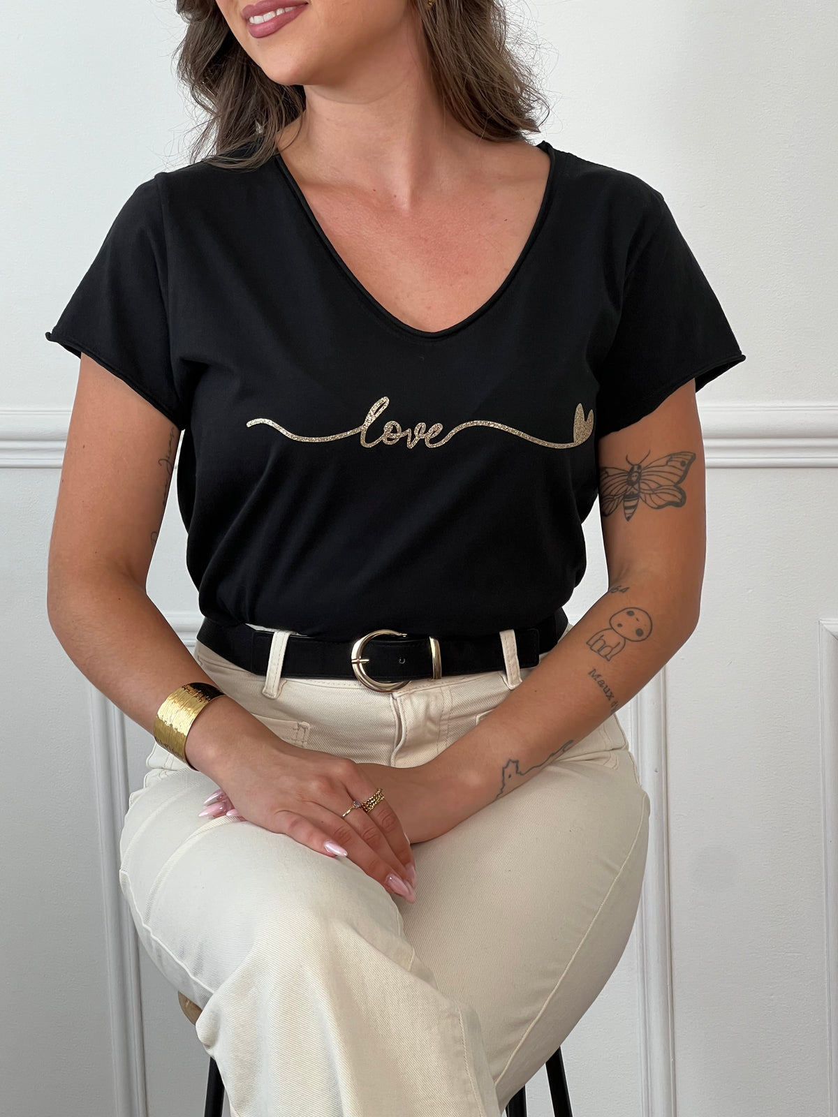 Ce tee-shirt noir "Clelia" allie confort et élégance avec ses manches courtes et son col rond classique. Sa touche distinctive, une inscription dorée sur le devant, apporte une subtile note de sophistication. Idéal pour un style décontracté mais soigné au quotidien.
