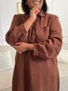 Cette robe courte en marron séduit par sa coupe ample et son col V à revers. Dotée de manches longues, de poches pratiques et de détails dorés aux poignets, elle allie confort et style au quotidien.