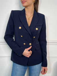 Optez pour une élégance intemporelle avec ce blazer bleu marine orné de boutons dorés. Sa coupe structurée et ses détails sophistiqués en font une pièce idéale pour un look chic et moderne.