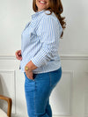 Une chemise grande taille à rayures bleues et écrues avec des manches longues et un col chemise. Boutonnée sur le devant et aux poignets, elle possède des rayures verticales et une poche avec un noeud au niveau de la poitrine.