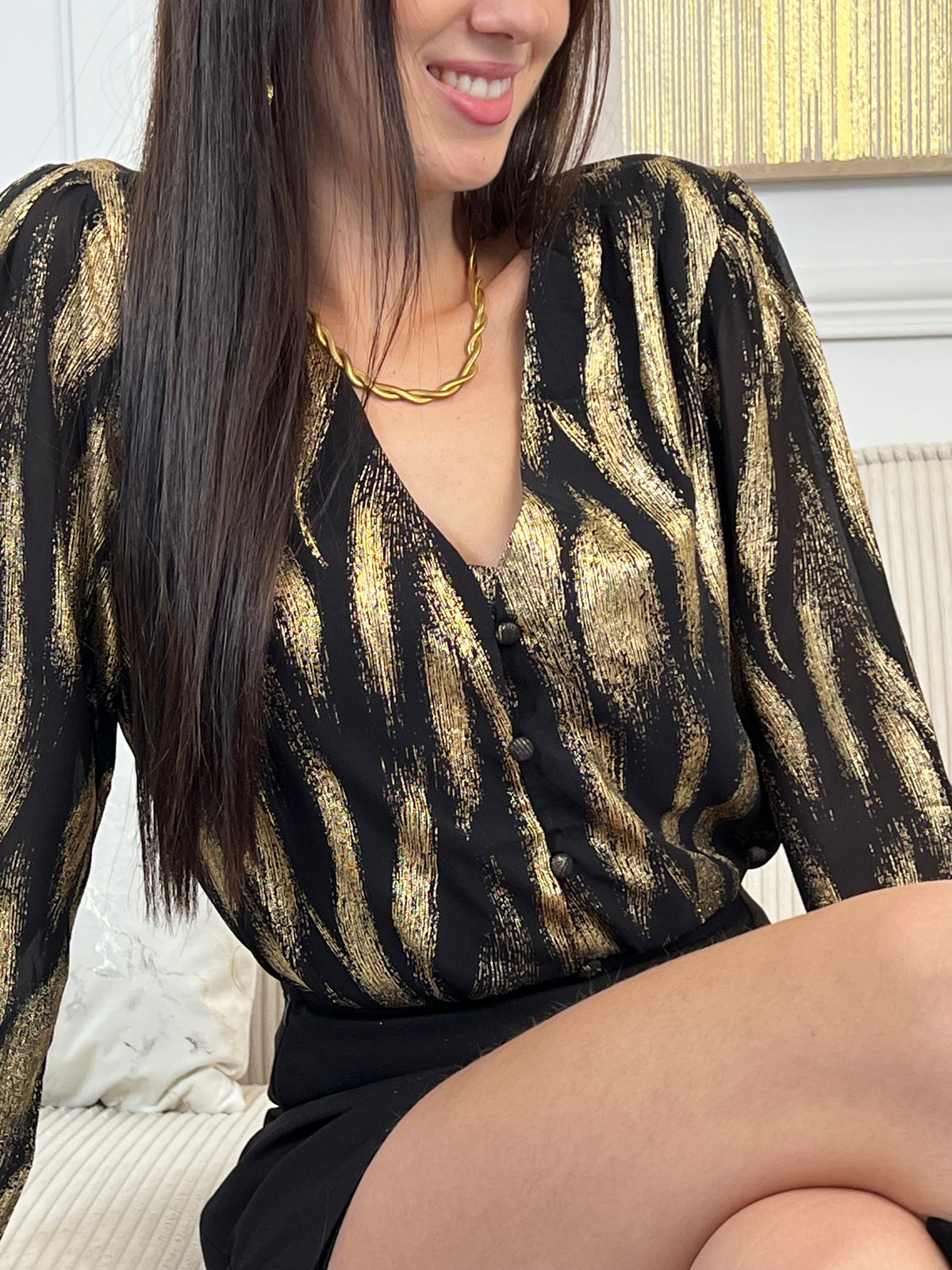 Découvrez la chemise Laina, une pièce festive qui allie élégance et confort. Avec son col V plongeant et ses manches longues ornées de volants délicats, elle crée une silhouette flatteuse et sophistiquée.