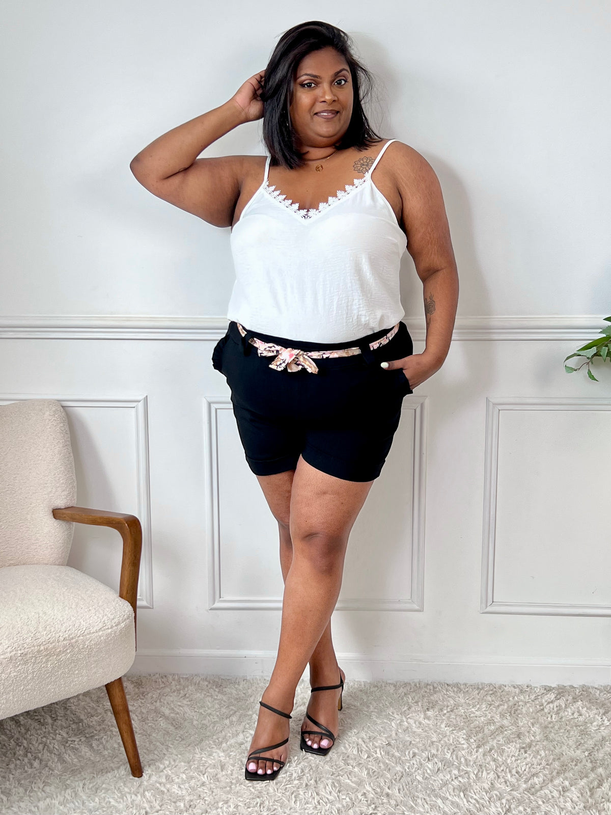 Short noir élégant avec des poches latérales ornées de volants délicats. Sa taille élastique assure un confort optimal, complétée par une ceinture amovible au motif fleuri pour une touche de fantaisie.