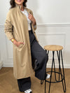 Trench beige femme avec ceinture, manches longues et col volanté pour une touche féminine. Boutons tout le long, doublure intérieure en carreaux vichy marron et écru, offrant élégance et confort. Coupe ample et deux poches latérales pratiques.