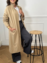 Trench beige femme avec ceinture, manches longues et col volanté pour une touche féminine. Boutons tout le long, doublure intérieure en carreaux vichy marron et écru, offrant élégance et confort. Coupe ample et deux poches latérales pratiques.