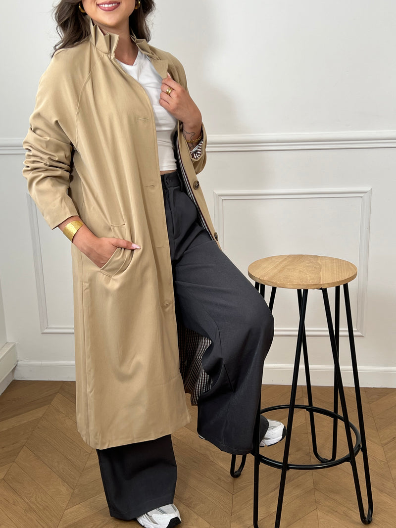 Trench beige femme avec ceinture, manches longues et col volanté pour une touche féminine. Boutons tout le long, doublure intérieure en carreaux vichy marron et écru, offrant élégance et confort. Coupe ample et deux poches latérales pratiques.