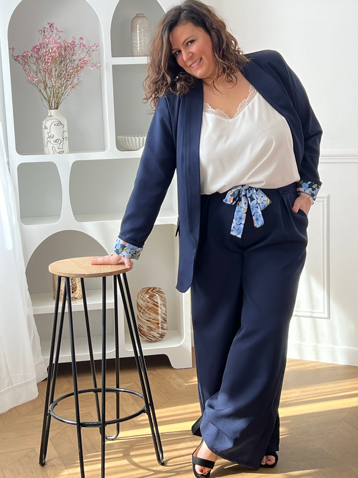 Blazer bleu marine grande taille Paola, conçu pour affirmer votre style avec élégance. Manches longues agrémentées de motifs fleuris aux poignets pour une touche de féminité. Épaulettes structurantes et doublure intérieure pour un confort optimal. Deux poches factices sur le devant complètent ce design intemporel. Parfait pour sublimer vos tenues professionnelles ou occasionnelles.