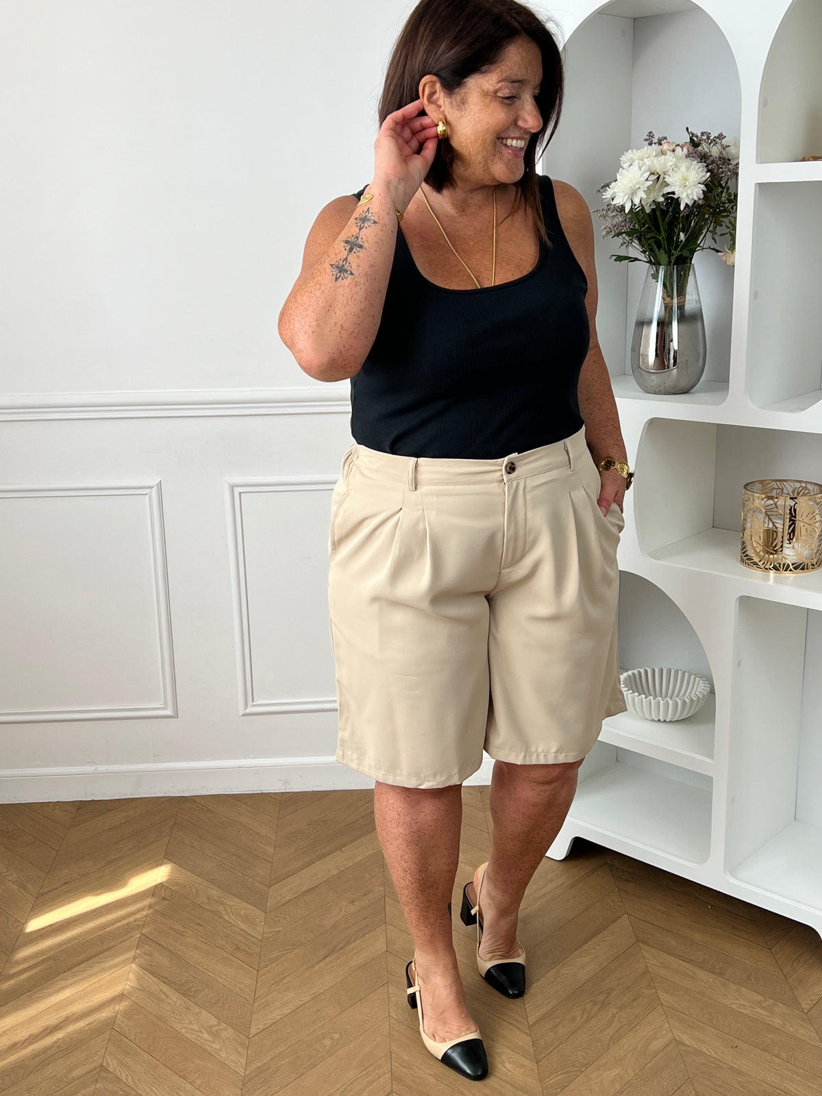 Bermuda beige grande taille pour femme, alliant confort et style pour la saison estivale. Équipé de deux poches latérales pratiques, d’une taille élastique au dos et de passants pour ceinture, il assure un ajustement parfait. Sa fermeture avec bouton et zip garantit un bon maintien. Polyvalent et facile à assortir, ce bermuda taupe est un indispensable du dressing casual chic.