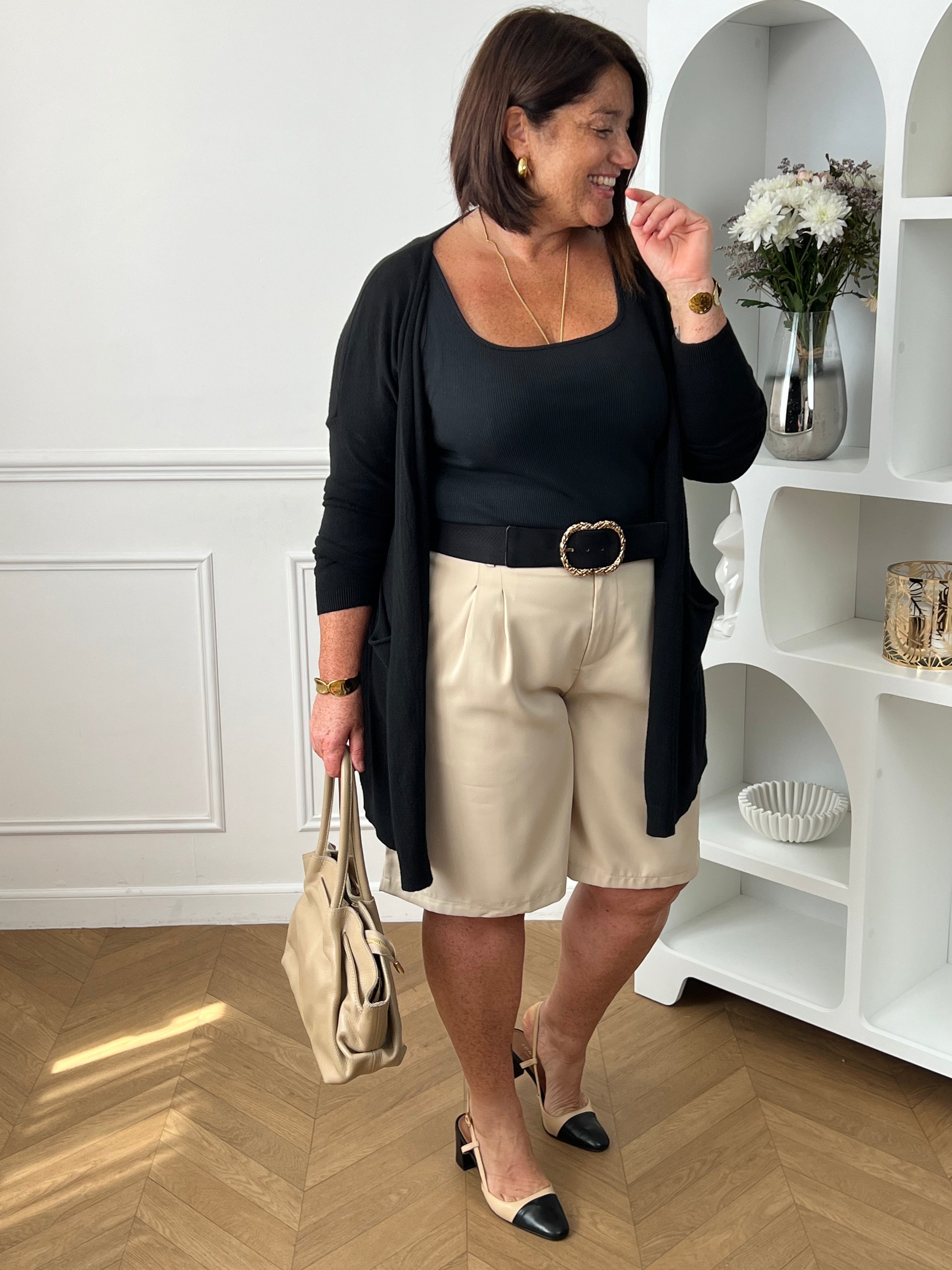 Bermuda beige grande taille pour femme, alliant confort et style pour la saison estivale. Équipé de deux poches latérales pratiques, d’une taille élastique au dos et de passants pour ceinture, il assure un ajustement parfait. Sa fermeture avec bouton et zip garantit un bon maintien. Polyvalent et facile à assortir, ce bermuda taupe est un indispensable du dressing casual chic.